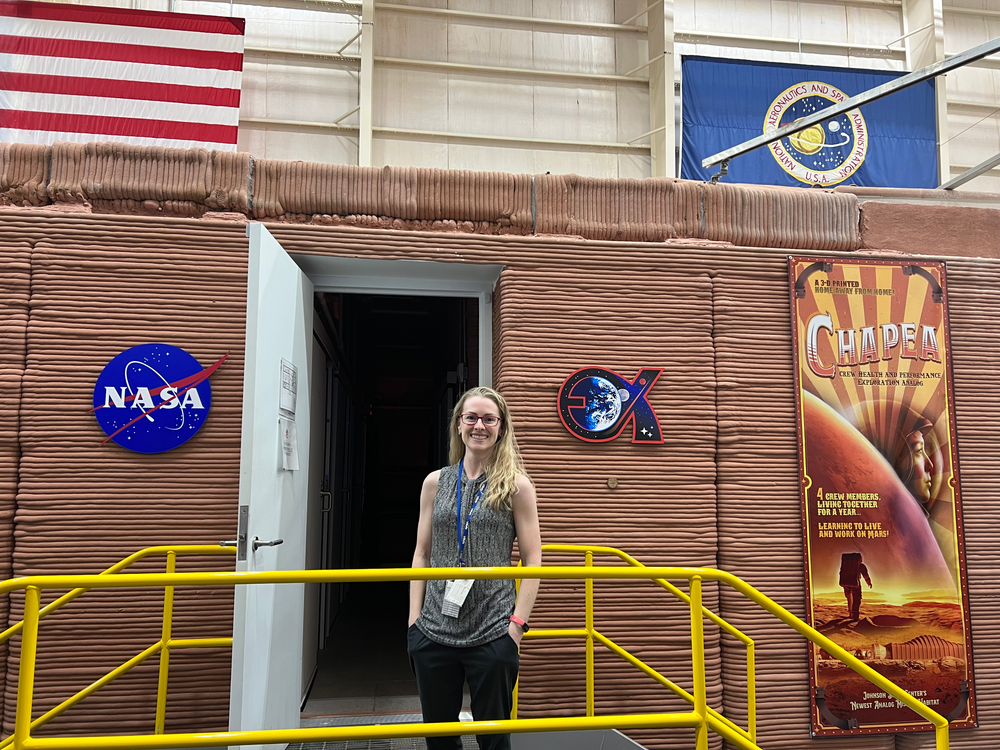 A woman stands in front of an open doorway.